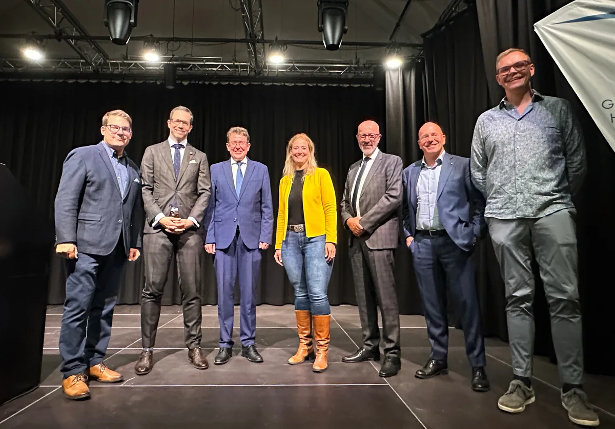 Gruppenfoto mit lächelnden Menschen auf einer Bühne.